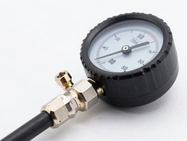 Macro shot of a high-precision digital pressure gauge testing an automotive AC hose fitting, bright studio lighting, crisp metallic details.