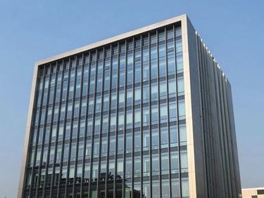 Modern office building facade in Gurugram, India, with clear blue sky, sleek glass and steel architecture, bright natural light, clean corporate navy and warm tones, sharp focus, 35mm.
