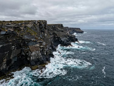 Ultra-wide aerial panorama of rugged ocean cliffs with white foam crashing on dark rocks, overcast sky