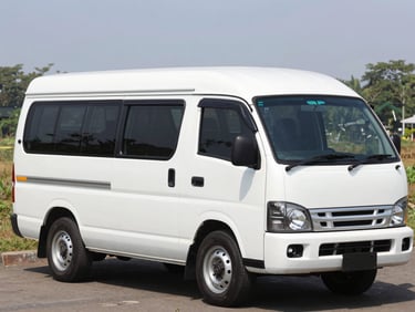 A clean white Isuzu ELF microbus parked in a sunny outdoor setting, natural Indonesian daylight, wide shot