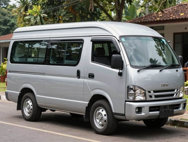 Mobil microbus Isuzu ELF berwarna silver terparkir di dekat area wisata alam Indonesia, pintu samping terbuka memperlihatkan kabin dalam yang lapang.