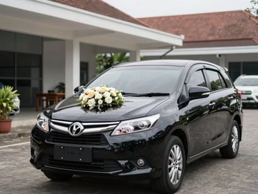 Mobil sedan mewah berwarna hitam dihiasi rangkaian bunga pernikahan cantik di kap depan, terparkir anggun di depan gedung pertemuan.