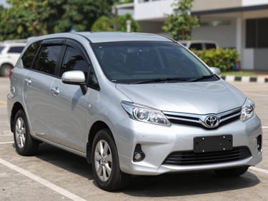 A clean silver Toyota Avanza parked in a bright outdoor parking spot, natural daylight, eye-level three-quarter shot