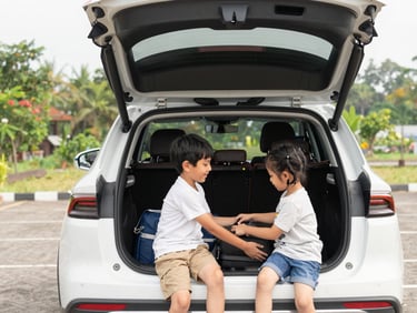 A family happily loading luggage into the spacious trunk of a clean modern SUV, bright Indonesian daylight, natural and warm family moment.