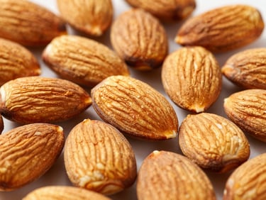 Macro shot of shelled golden almonds on a clean surface, bright natural light, sharp focus on rich textures
