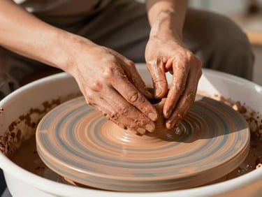 Close-up of artisan hands shaping clay on a pottery wheel in a sunlit studio, warm terracotta tones, shallow depth of field.