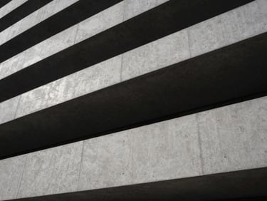 Modern architectural exterior with sharp lines and concrete textures, emphasizing spatial choreography under diffused light.