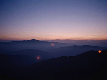 Vast atmospheric landscape of a distant horizon at twilight, misty mountain peaks, low-key backlit lighting, soft lens flares.