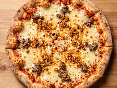 Close-up of a Neapolitan pizza with 'nduja sausage and roasted red peppers, vibrant orange and red tones, intense firelight glow.