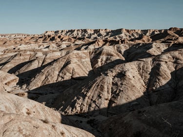 Wide, desaturated panoramic landscape of the Utah high desert near Vernal, dramatic rock formations, harsh chiaroscuro sunlight, deep shadows.