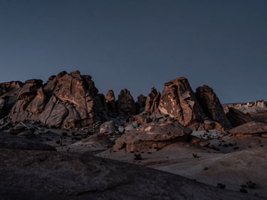 A desaturated panoramic view of the Utah high desert at twilight, jagged rock formations silhouetted against a deep slate sky, low-key directional lighting.