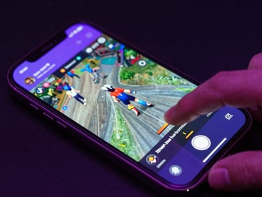 Overhead close-up of a smartphone screen showing a TikTok gaming clip mid-scroll, electric violet light from a gaming monitor reflecting on the phone surface, dark background, finger hovering over screen