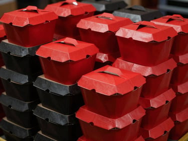 High-contrast commercial photography of stacks of clean red and charcoal cardboard takeout boxes in a professional warehouse, dramatic studio lighting with deep shadows, sharp focus, 35mm