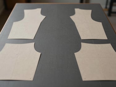 Symmetric shot of a clean, modern pattern cutting table with technical garment templates, soft studio lighting, muted charcoal tones