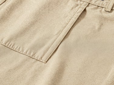 Macro close-up of premium warm beige chino fabric texture, sharp focus on clean stitching and weave, soft diffused daylight, 35mm lens