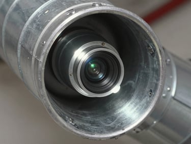 Macro close-up of a high-definition duct inspection camera showing the clean metallic interior of a residential air duct, sharp utility lighting reflecting on galvanized steel.