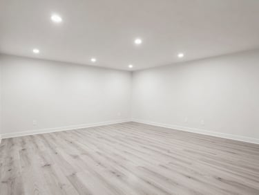 Bright, eye-level shot of a finished basement living room, featuring clean drywall, recessed lighting, and modern light gray flooring.