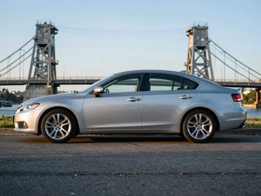 Clean silver sedan parked near the historic Stillwater Lift Bridge at golden hour, low sun, crisp focus.