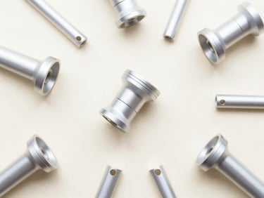 Minimalist overhead flat-lay of clean, brightly lit custom aluminum parts on a soft pastel cream surface, sharp focus, 50mm