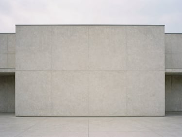 Straight-on architectural shot of minimalist concrete building facade under soft overcast daylight, clean geometric lines, vast negative space, muted tones, quiet atmosphere.
