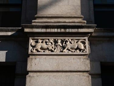 Architectural detail of a classic stone financial institution, focusing on a carved stone relief, high contrast, deep shadows.