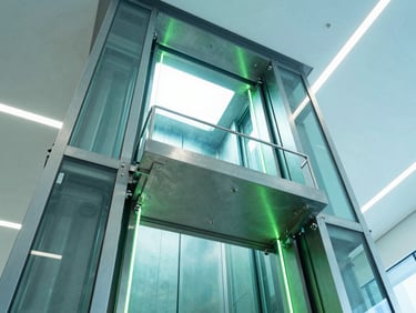 Sleek modern glass elevator shaft with a heavy industrial steel lift platform, dramatic high-key lighting with cool teal reflections and bright neon green laser-line accents, low-angle architectural perspective.