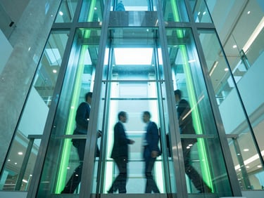 Low-angle architectural photography of a sleek glass passenger elevator shaft reflecting cool teal and neon blue ambient light, corporate professionals in motion, bright high-key interior lighting with neon green accents, wide-angle lens