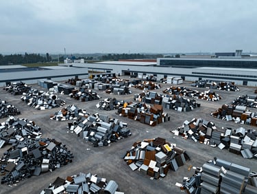 Aerial view of a large, organized metal scrap yard with various piles of sorted non-ferrous metals, industrial corporate feel, cool overcast daylight, industrial editorial photography.