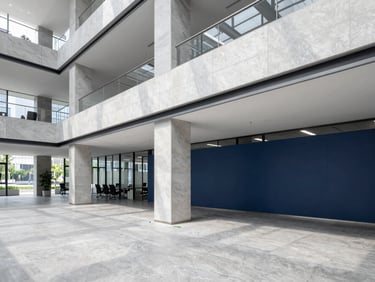 Wide shot of a modern, clean corporate office interior with structured architectural lines and cool slate tones, bright natural daylight.