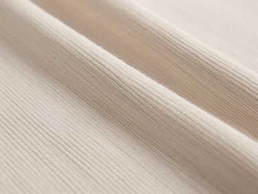 Macro close-up of 1x1 and 2x2 rib knit fabric, showing clean vertical elasticity and stitch definition, neutral cotton tones.