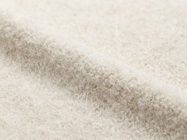 Macro shot of soft brushed fleece texture, clean industrial daylight, showing dense fiber structure, neutral cotton tones.