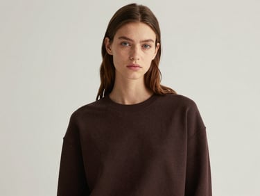 Studio portrait of a young model under soft natural light, minimalist styling, rich muted tones, high-end magazine style.
