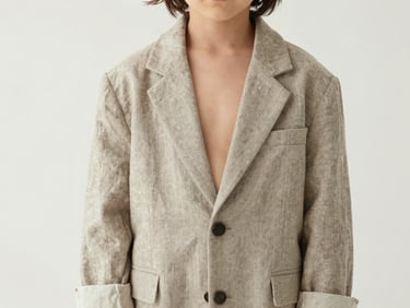 Editorial close-up of a child wearing a neutral linen oversized blazer, soft natural lighting, high-fashion styling, minimalist studio setting.