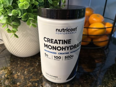 Creatine container on kitchen counter with oranges and greenery promoting women’s wellness