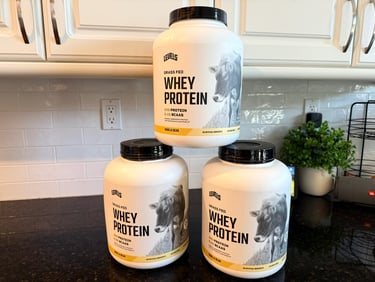 Grass fed Levels whey protein containers on a kitchen counter.