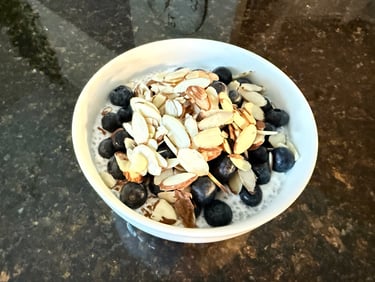 white bowl of chia seed pudding on counter with blueberries and almonds
