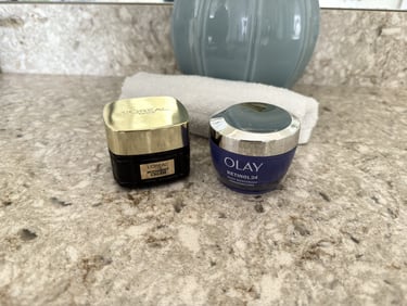 Olay night cream and RoC moisturizer with white washcloth on counter, calm skincare scene