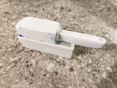 Pumice stone toilet cleaner resting on its container on a bathroom counter ready to scrub hard water