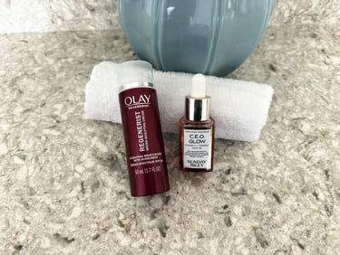 Sunday Riley C.E.O. Glow oil and Olay moisturizer with white washcloth on counter, morning skincare