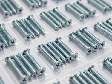 Organized rows of heavy-duty galvanized steel screws, bolts, and anchors in clear heavy-gauge retail packaging, bright industrial lighting, sharp focus, 35mm