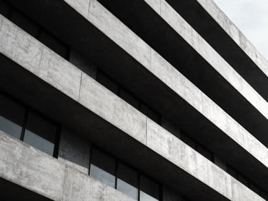 Abstract architectural geometry of a modern banking headquarters, sharp directional light, concrete and steel, high-contrast.