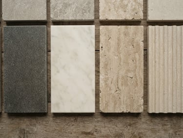 Flat-lay overhead shot of architectural stone samples, honed granite and polished marble slabs side by side, natural overcast daylight, desaturated earth tones, tactile textures