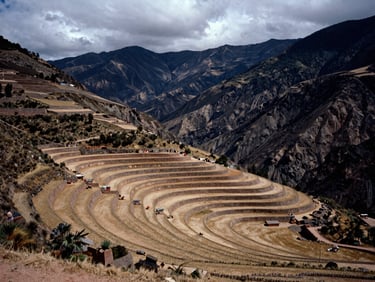 Wide view of agricultural terraces in Ollantaytambo, dramatic overcast mountain daylight, earthy tones