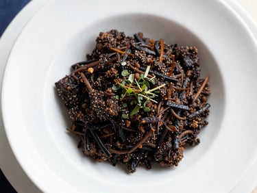 Close-up of a dark, rich Batak saksang dish in a white ceramic bowl, garnished with fresh herbs, bright natural window light, top-down flat lay, without gota.