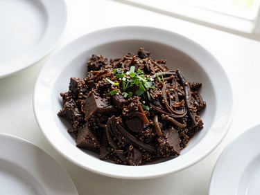 Close-up of a dark, rich Batak saksang dish in a white ceramic bowl, garnished with fresh herbs, bright natural window light, top-down flat lay.