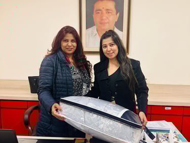 two women standing in front of a desk with a surfboard