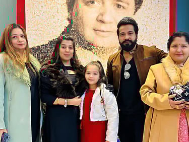 a family posing for a picture in front of a large poster
