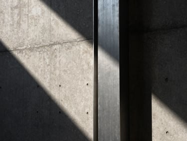 Extreme close-up of a raw concrete wall intersecting with a brushed steel column under harsh raking sunlight, deep shadows, architectural photography style.