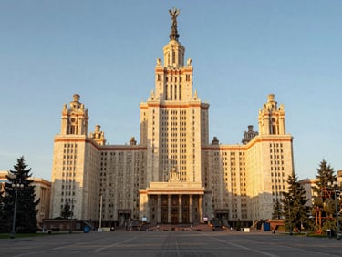 Wide environmental shot of Moscow State University's main building facade at golden hour, natural warm side light raking across the neoclassical stone columns, foreground empty plaza, no people, documentary framing