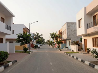 Wide-angle street view of Rajouri Garden neighborhood in soft afternoon light, clean tree-lined avenue, modern residential architecture, 35mm lens